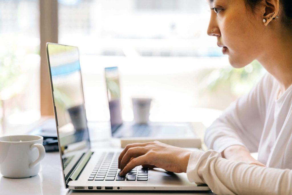 Woman browsing video library on laptop in coffee shop